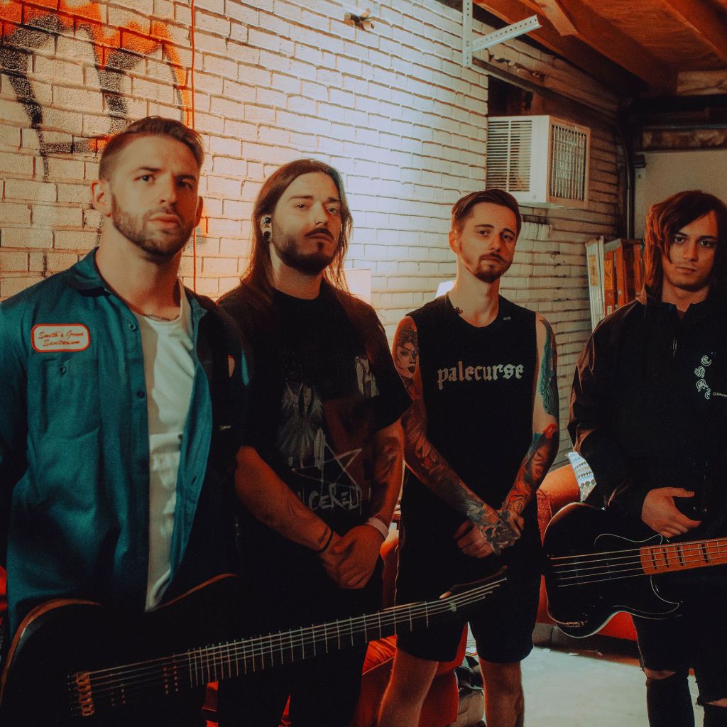 Four musicians posing in a room with a brick wall, each holding instruments. The scene features a relaxed underground vibe.