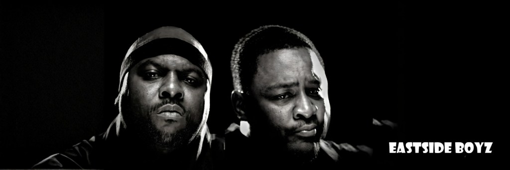 A black and white image featuring two men with serious expressions, portraying a strong presence. On the right side, the text 'EASTSIDE BOYZ' is prominently displayed.
