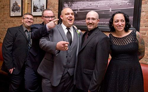 Five individuals posing together for a photo, smiling and enjoying a celebratory moment in a stylish indoor setting.
